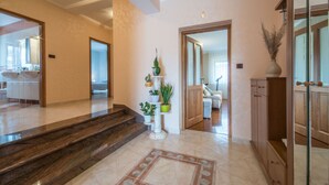 A spacious hallway with a marble staircase, a potted plant arrangement, and a wooden cabinet. - Wonderful new villa, lush fenced garden, private pool (Pazin)