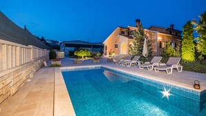 A swimming pool with lounge chairs and a stone wall. - Wonderful new villa, lush fenced garden, private pool (Pazin)