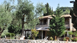 Una villa con muro de piedra, sillones de descanso y una pérgola.