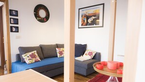 A living room with a blue sofa, grey sofa, and a small table with candles. There are framed pictures on the wall and a mirror above the sofas. - Casa Bella Skyline (Bologna)