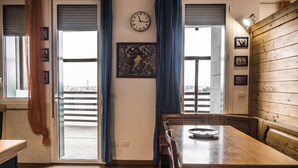 A dining area with a wooden table, chairs, a clock, and a view through the sliding doors. - Casa Bella Skyline (Bologna)
