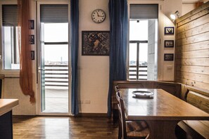 Enjoy meals with a city view from this dining area featuring a table and chairs, framed artwork, and a balcony access.