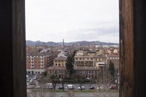 Panoramic city view from a window, showcasing a mix of architectural styles and a bustling urban scene.