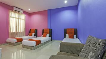 Habitación de hotel con tres camas, un sofá y una ventana con cortinas.