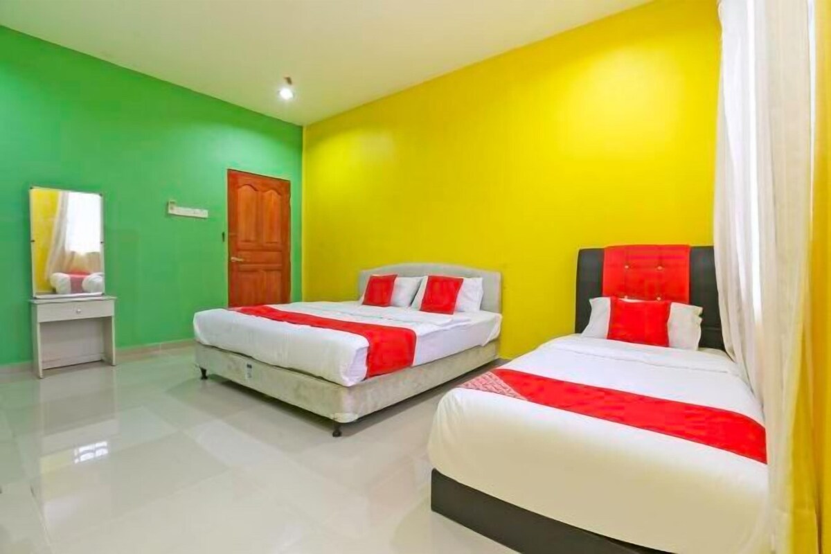 A hotel room with two beds, green walls, and a wooden door.
