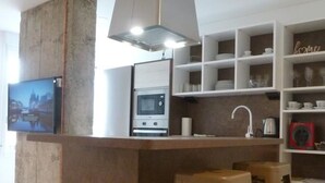 A modern kitchen with a central island, bar stools, a microwave, and a hanging light fixture. - The stop - 4.La PSD1.7 (Zaragoza)