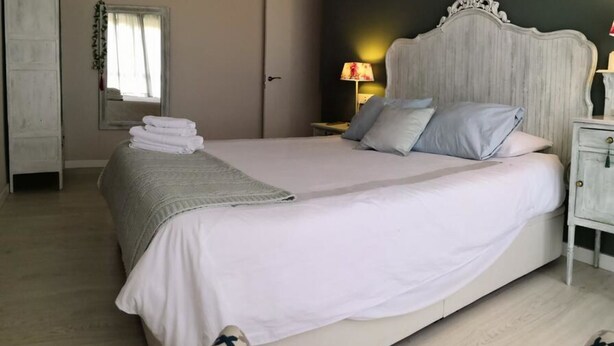 A bedroom with a large bed, a nightstand, a dresser, and a chandelier. - The stop - 4.La PSD1.7 (Zaragoza)
