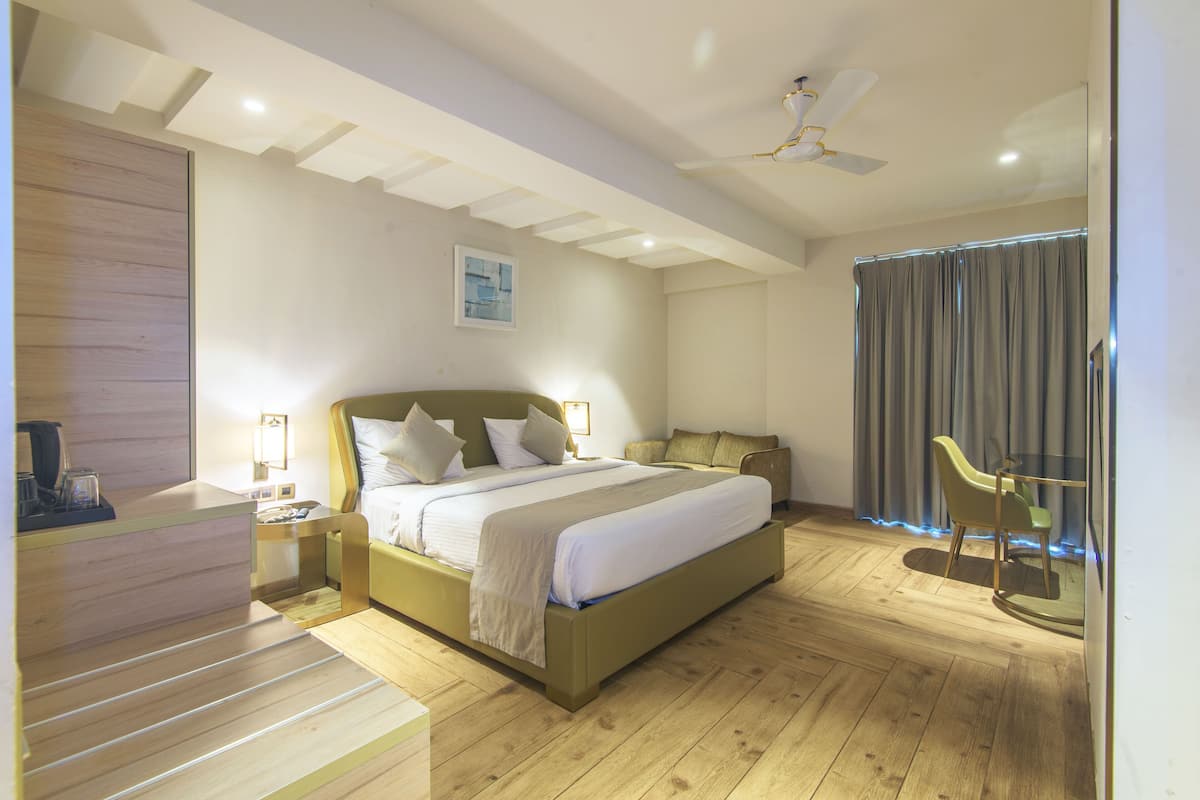 A modern hotel room with a large bed, a desk, and a chair.