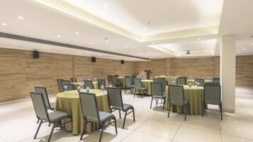 A conference room with round tables and chairs, equipped with water bottles.