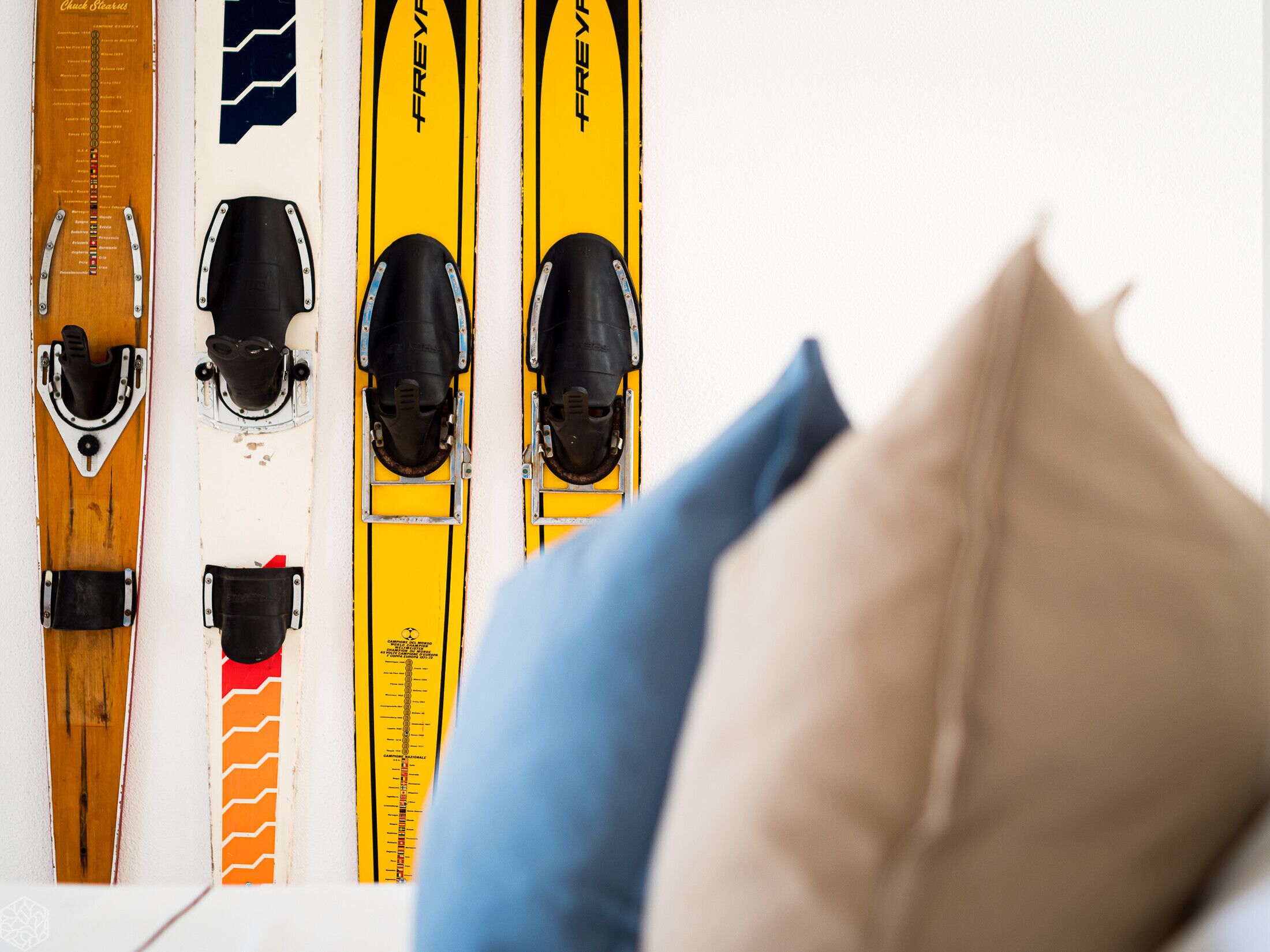 Einige Skier, die an einer Wand lehnen, wobei ein Kissen die Sicht teilweise verdeckt.