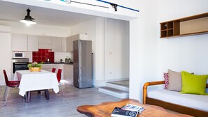 A modern apartment with a dining area, kitchen, and living room. - Villetta Bianca (Olbia)