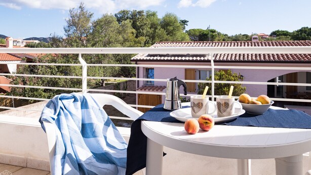 A balcony with a table set for breakfast, including peaches, a kettle, and cups. - Villetta Bianca (Olbia)