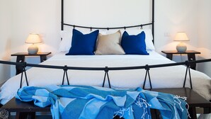 A bed with a canopy, two bedside tables with lamps, and a blue blanket on the floor. - Villetta Bianca (Olbia)