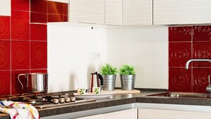 A modern kitchen with a gas stove, stainless steel pots, and potted plants on the counter. - Villetta Bianca (Olbia)