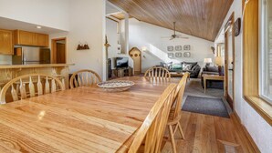 A spacious dining area with a wooden table and chairs, a kitchen with wooden cabinets, a living room with a sofa and a TV, and a ceiling fan. - 13 Modoc-Sunriver, Oregon: Hot Tub, BBQ, WiFi, Ping Pong, Foosall, SHARC Aquatics, Tubing Hill, Mt. Bachelor, Golf, Deschutes River, Tennis, Bike Paths (Sunriver)