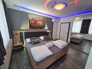 Una habitación de hotel moderna con una cama grande, un cuadro de paisaje urbano y un diseño de techo original.