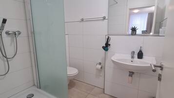 Une salle de bain moderne avec une douche à parois de verre, un lavabo blanc et des toilettes.