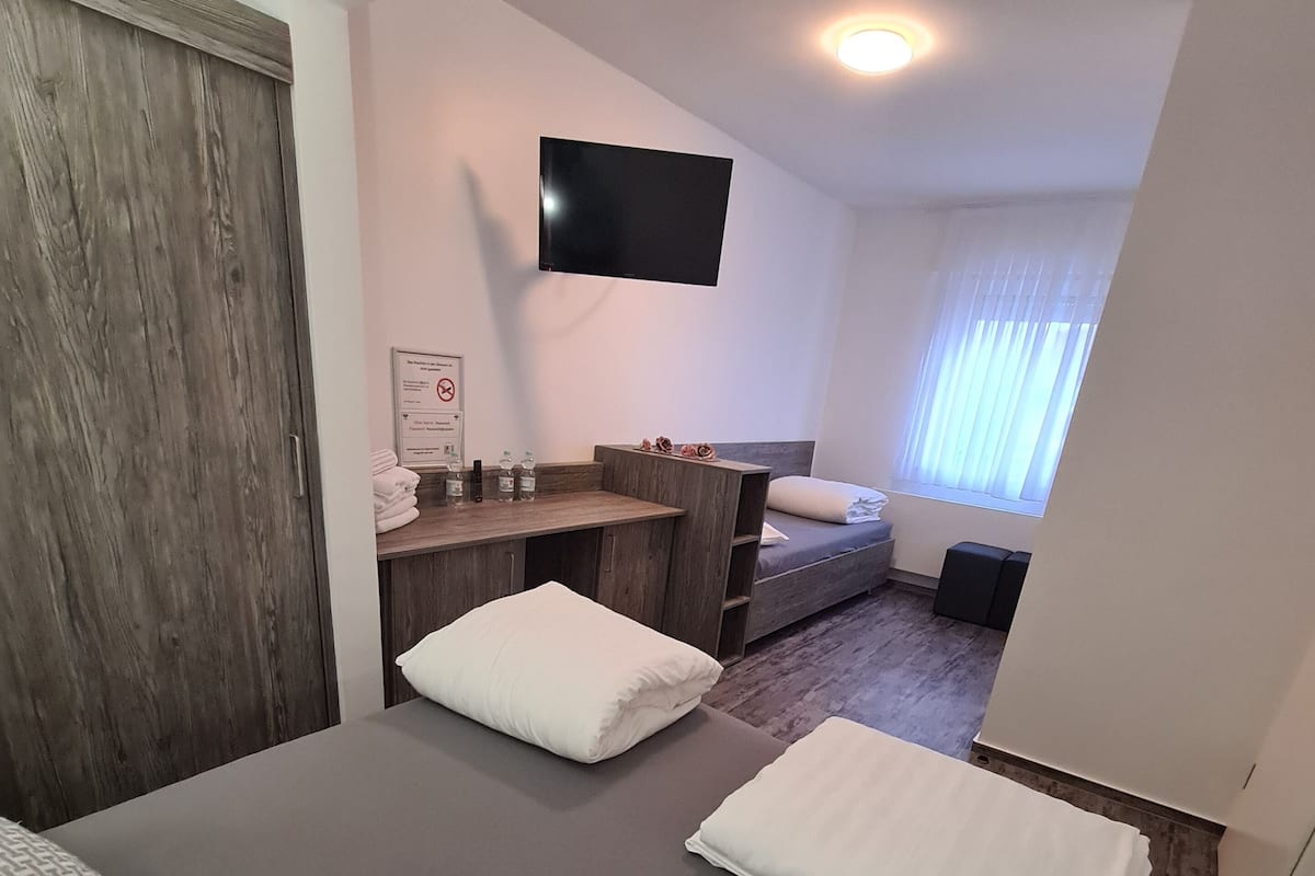 A hotel room with a bed, a desk, a TV, and a window.