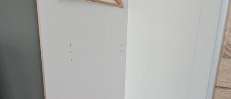Een kleine, zwarte koelkast in een hoek van een kamer met witte muren en een houten vloer.