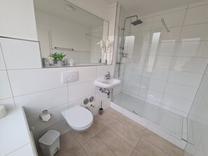 Une salle de bain moderne équipée de toilettes, d’un lavabo et d’une douche.