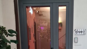 L’entrée d’un hôtel, avec une porte en verre, un paillasson et un tapis d’entrée.