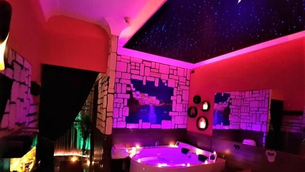 Une pièce avec un mur en pierre, un jacuzzi et un plafond décoré de motifs étoilés.