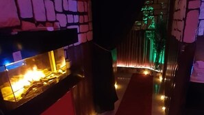 Un couloir avec un mur en pierre d’un côté et un foyer de l’autre.