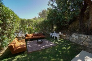 A patio area with a brown sofa, a fire pit, and a table with chairs.