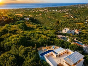 A residential area with a swimming pool, solar panels, and a view of the sea. - Sea Horizon Villa Ikaros by DomisiGroup (Ag. Triada)