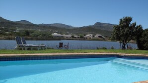 Une piscine offrant une vue dégagée sur un lac et des montagnes en arrière-plan.