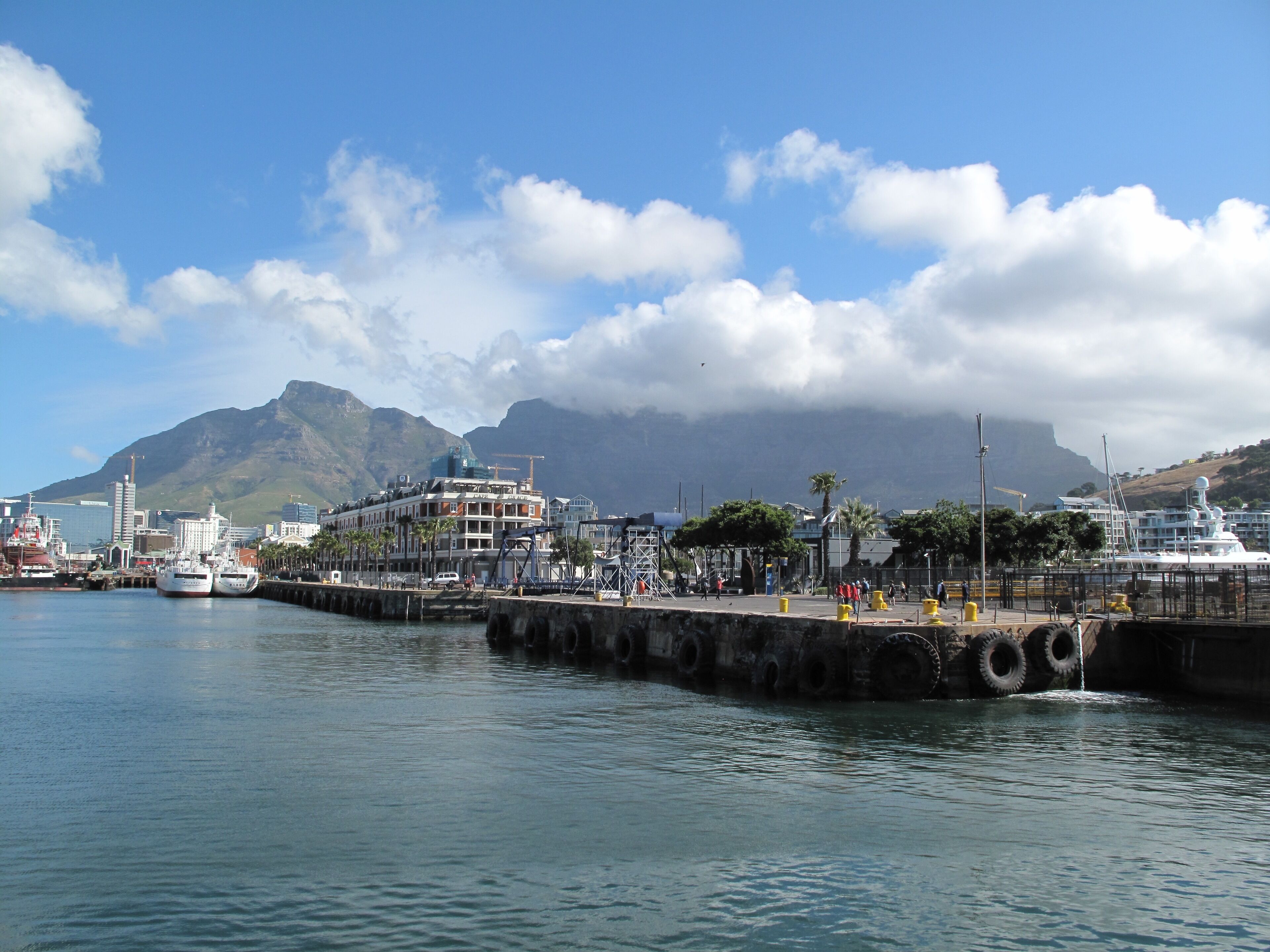 A harbor with boats, a pier, and buildings in the background.