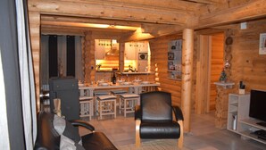 A log cabin interior with a dining area, kitchen, and living room. - La Bresse Lodge - Air-Conditioned Log Cabin (La Bresse)