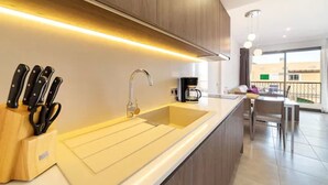 A modern kitchen with a large island, a coffee maker, and a view of the outside. - Hotel Paradise Residencial (Capdepera)
