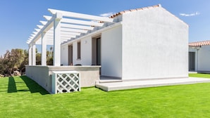 Een modern huis met een witte gevel, een overdekt terras en een verzorgd gazon.