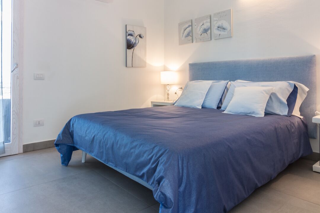 A bedroom with a large bed, a nightstand, and wall art.