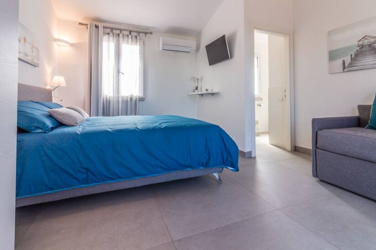 Een slaapkamer met een bed, een televisie en een schilderij aan de muur.