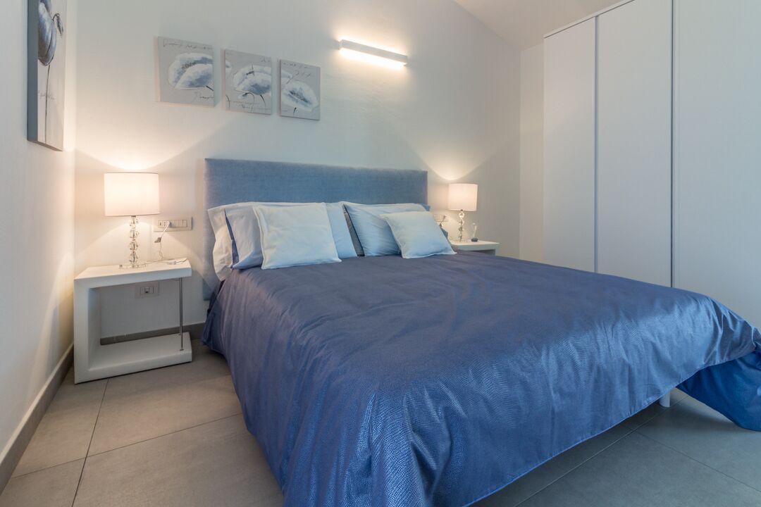 A bedroom with a large bed, two bedside tables with lamps, and a wardrobe.