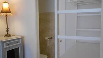 A bathroom with a toilet, a small cabinet, and a lamp.