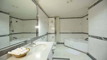 A modern bathroom with a large mirror, a sink, a toilet, and a bathtub.