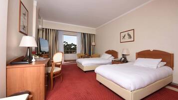 A hotel room with two beds, a desk, a chair, and a TV.