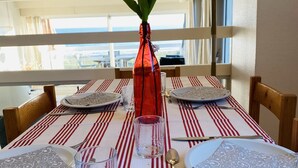 Mesa de jantar posta com pratos, talheres e um vaso com flores.