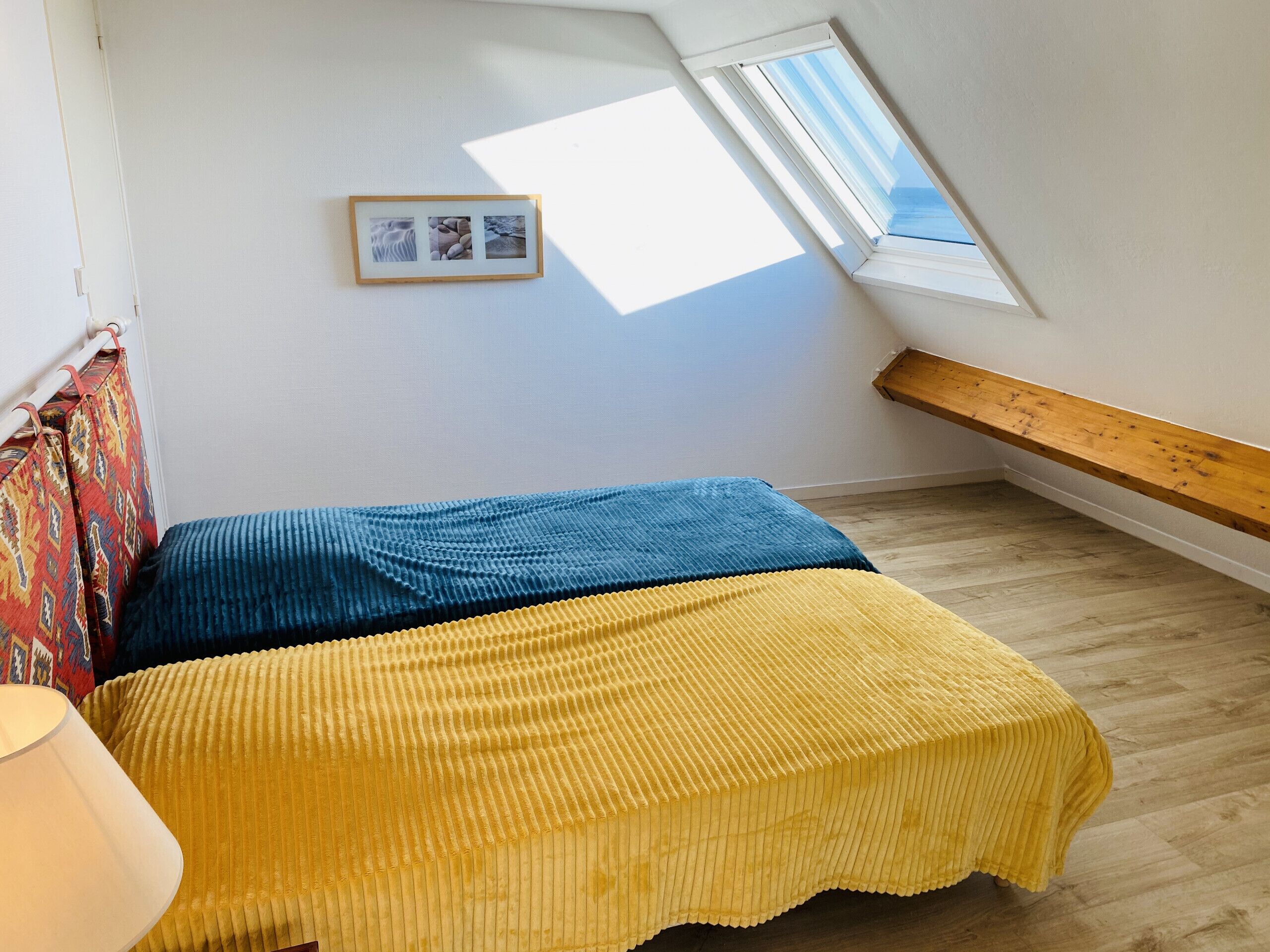 Une chambre à coucher avec un lit, une fenêtre et un banc en bois.