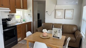 A compact kitchen with wooden cabinets, a stove, and a dining area with a table and chairs.