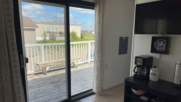 A room with a sliding glass door leading to a balcony, a coffee maker, and a framed picture on the wall.