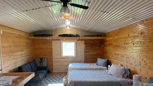 A compact cabin with two beds, a small seating area, and a wooden interior.