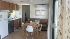 A compact kitchen with wooden cabinets, a white refrigerator, and a dining area with a wooden table and white chairs.