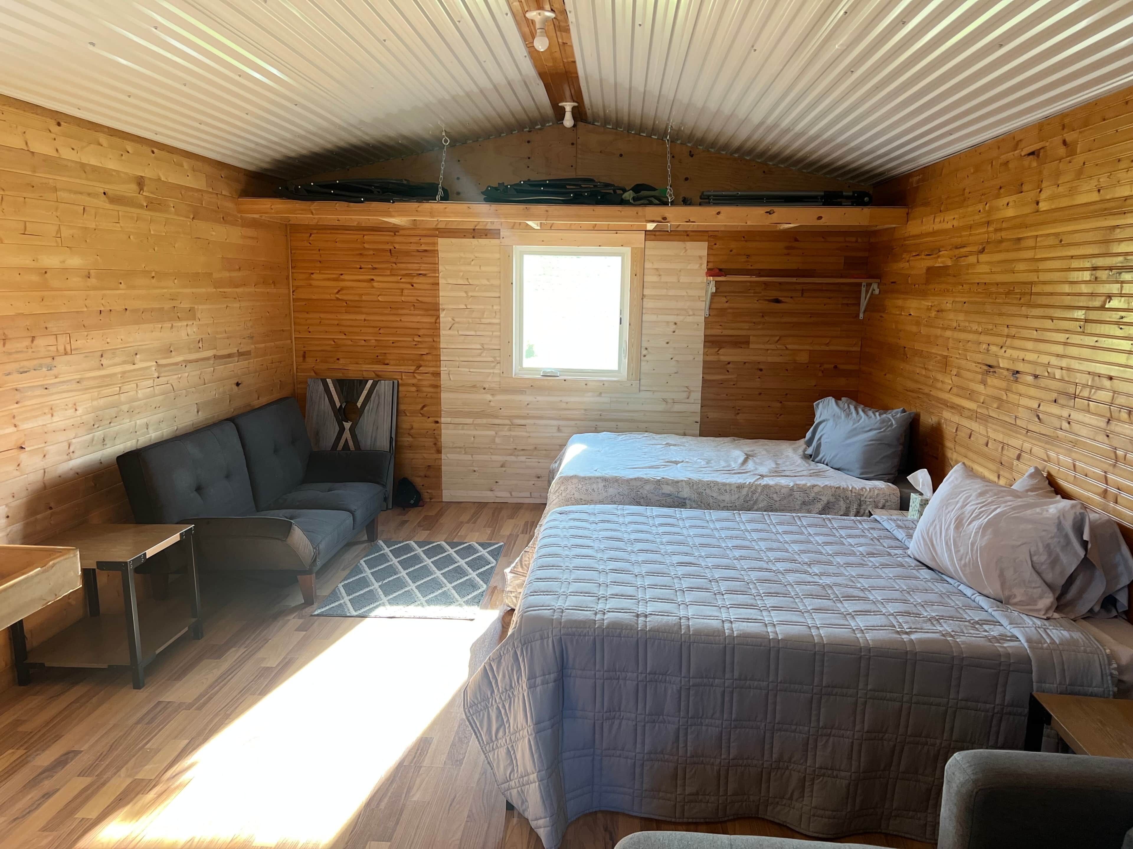 A cozy cabin room with a loft bed, a sofa, and a small table.