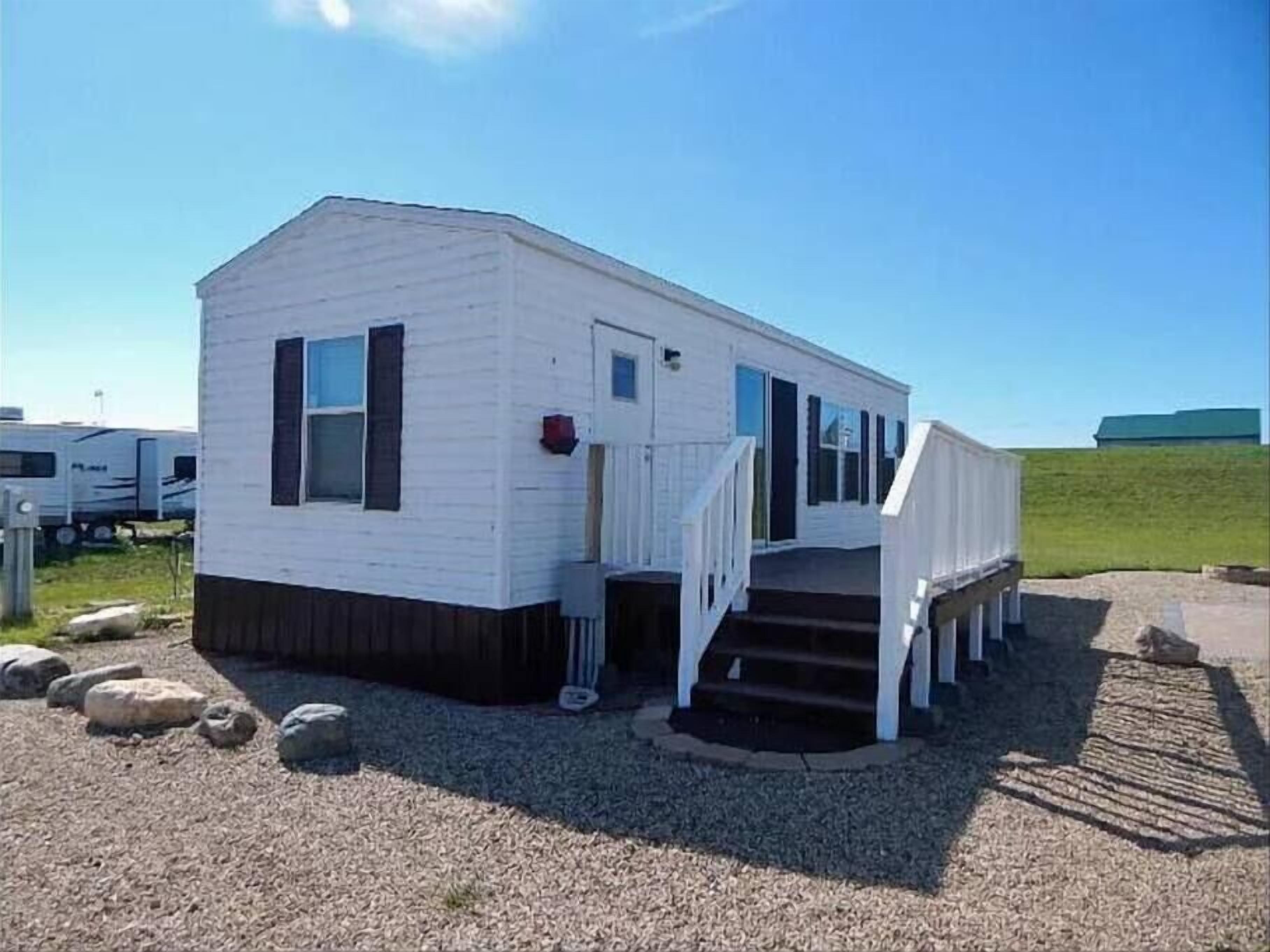 A single-story mobile home with a front porch and a small set of steps leading to the entrance.