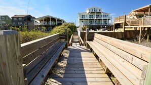 A wooden boardwalk leading to a beachfront property with multiple levels and a balcony. - Enjoy Sounds Beachy, an 8-bedroom haven in North Topsail Beach, NC with stunning water views. (North Topsail Beach)