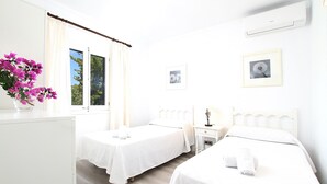 A hotel room with two beds, a desk, a chair, a window with curtains, a vase of flowers, and a framed picture on the wall. - PLANA. Fantastic villa in a very quiet area (Pollensa)
